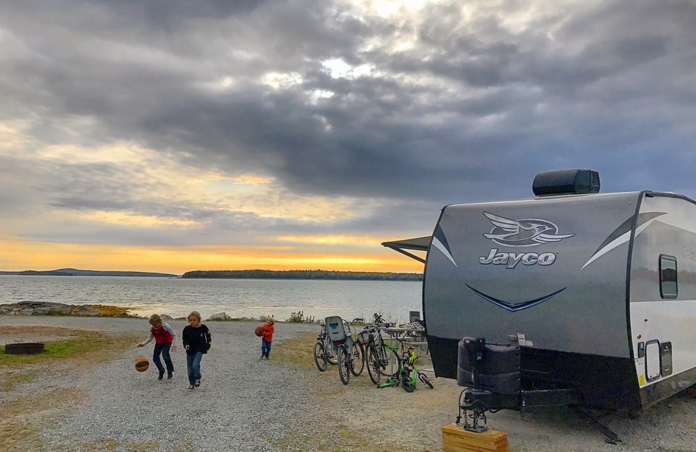 A travel trailer in front of a body of water